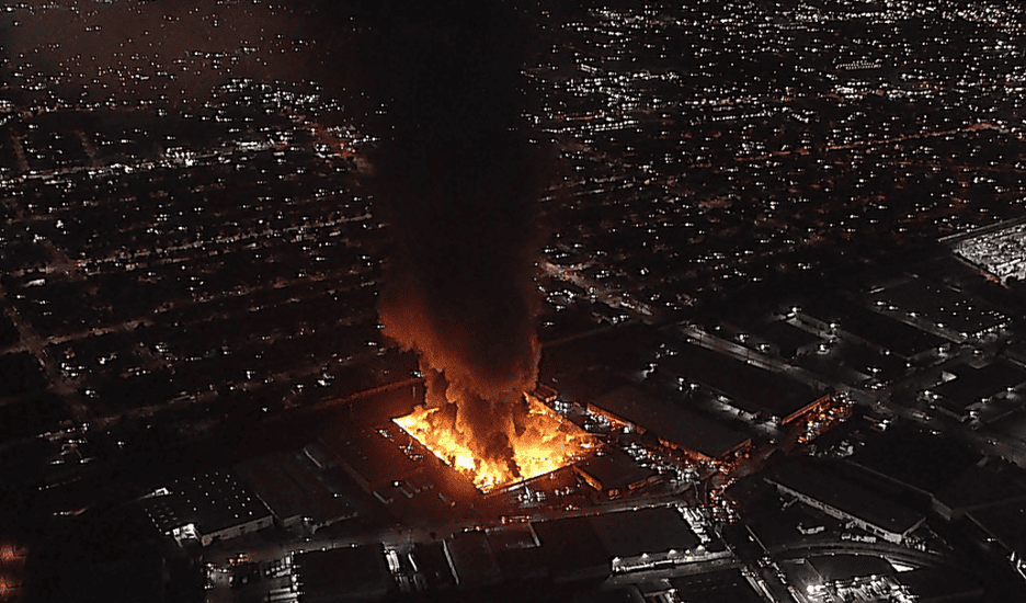 Industrial warehouse fire blows thick black smoke into the air